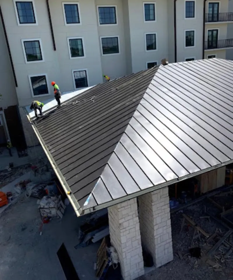 Crew installing standing seam metal roof panels on a commercial project in Ashtabula